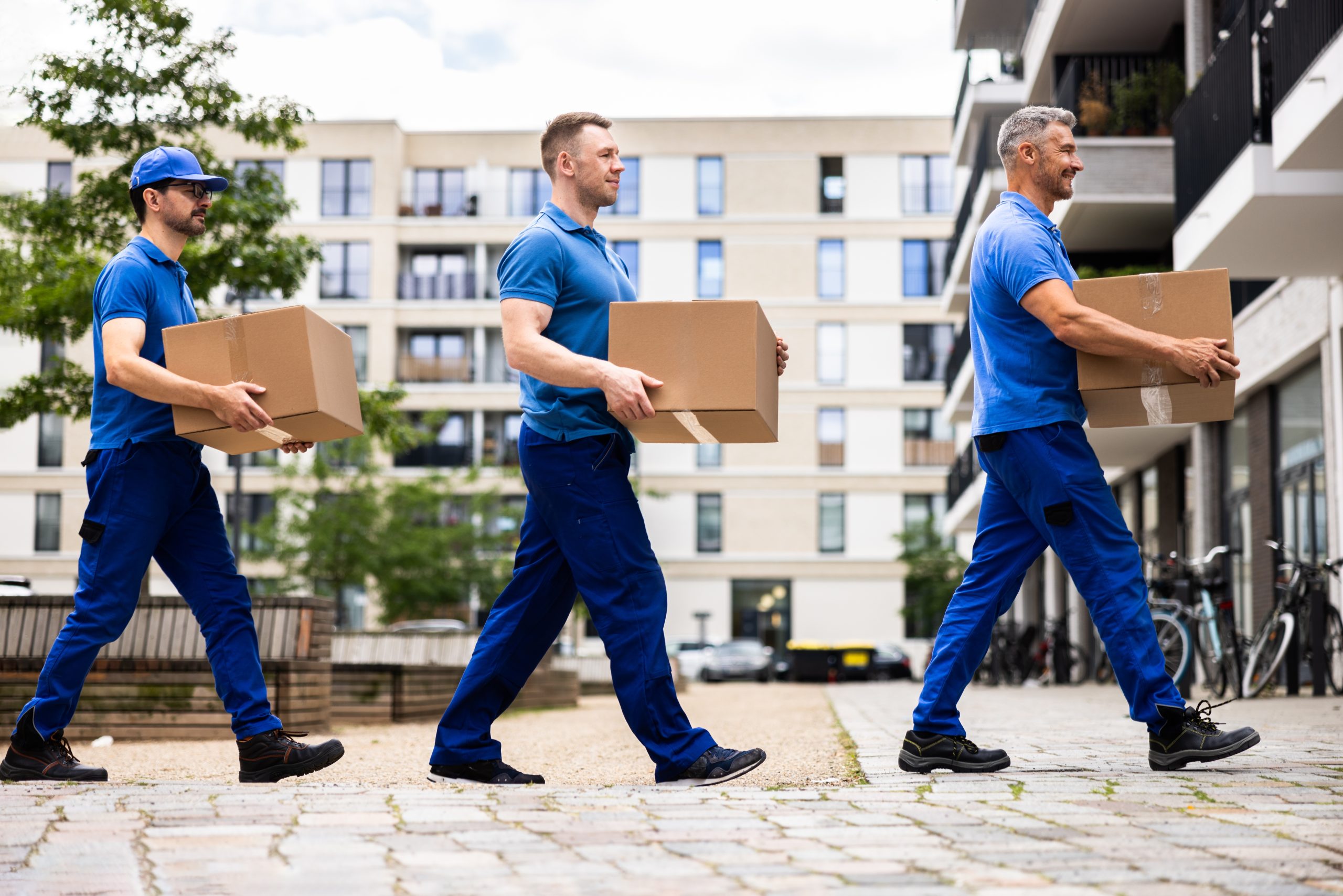 Three movers walking in a line, each carrying a box.