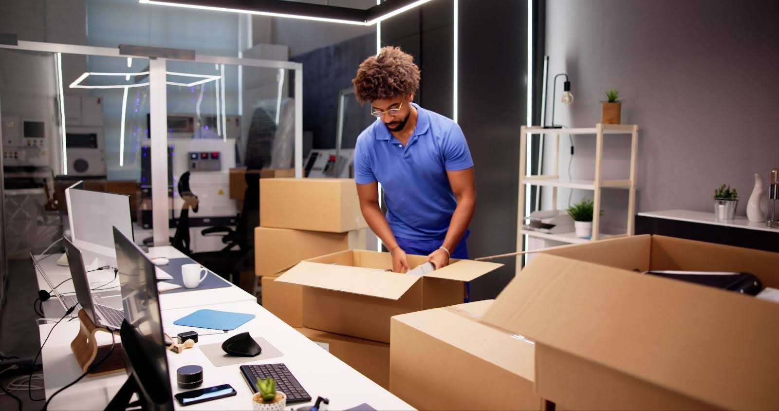 Man in blue polo packing up boxes in his office.