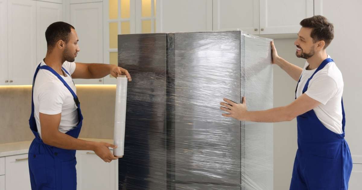 Two Lorain Ohio movers wrapping a fridge with premier packing materials. 